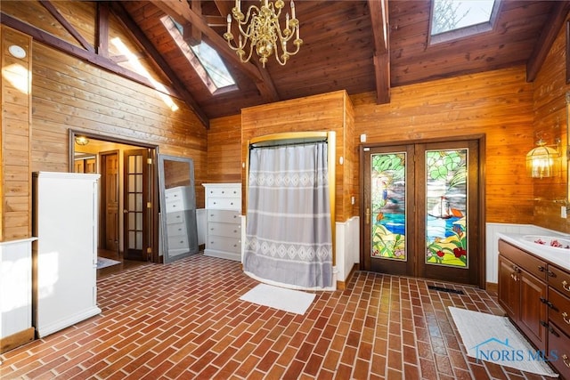 interior space featuring wood walls, a skylight, and beam ceiling