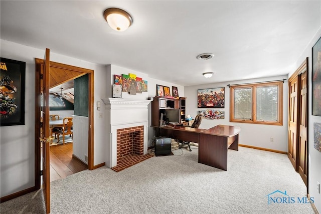 home office featuring a fireplace with flush hearth, carpet, visible vents, and baseboards