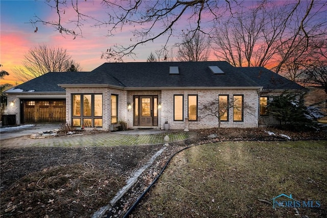 view of front of home with a shingled roof, brick siding, driveway, and a garage