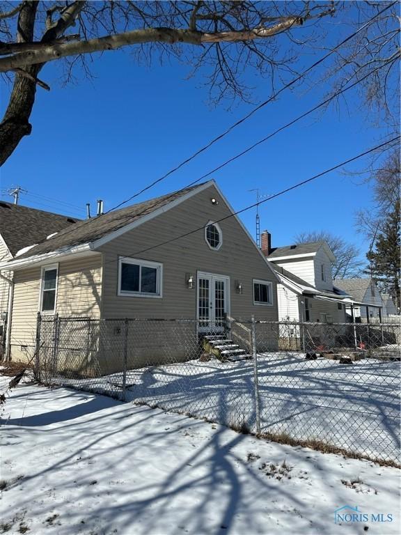 snow covered rear of property featuring crawl space and a fenced front yard