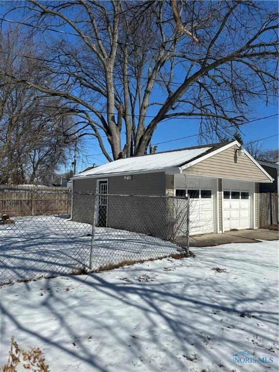 snow covered garage with a garage and fence