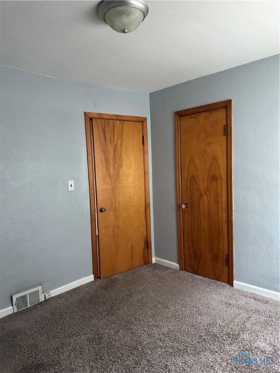 unfurnished bedroom with carpet floors, a closet, visible vents, and baseboards