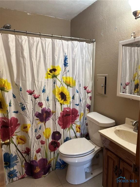 full bath featuring a textured wall, toilet, a shower with curtain, tile patterned flooring, and vanity