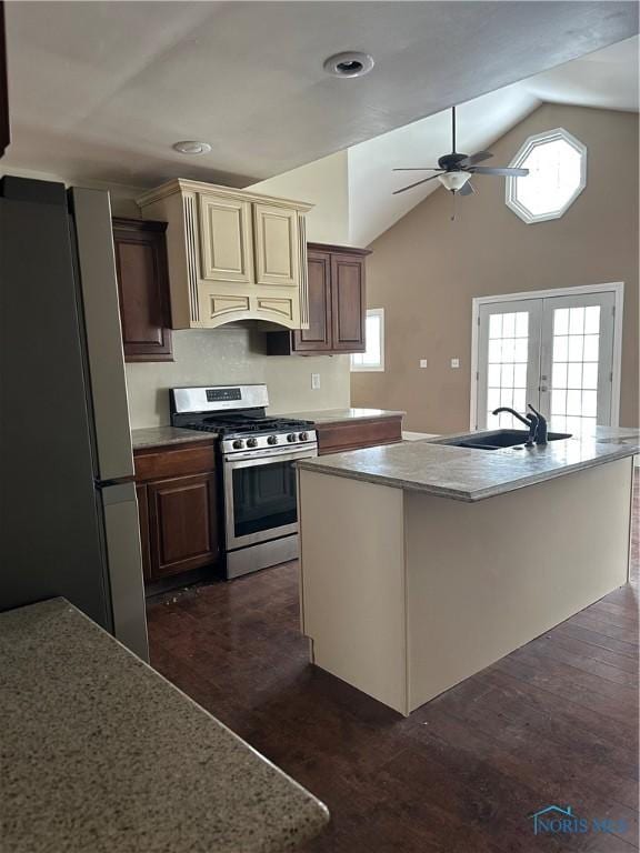 kitchen featuring an island with sink, appliances with stainless steel finishes, dark wood-style flooring, light countertops, and a sink