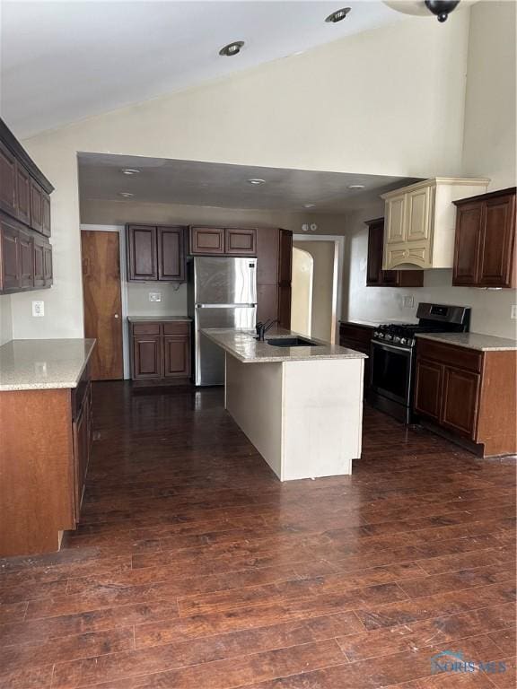 kitchen with light countertops, appliances with stainless steel finishes, dark wood-type flooring, and a kitchen island with sink