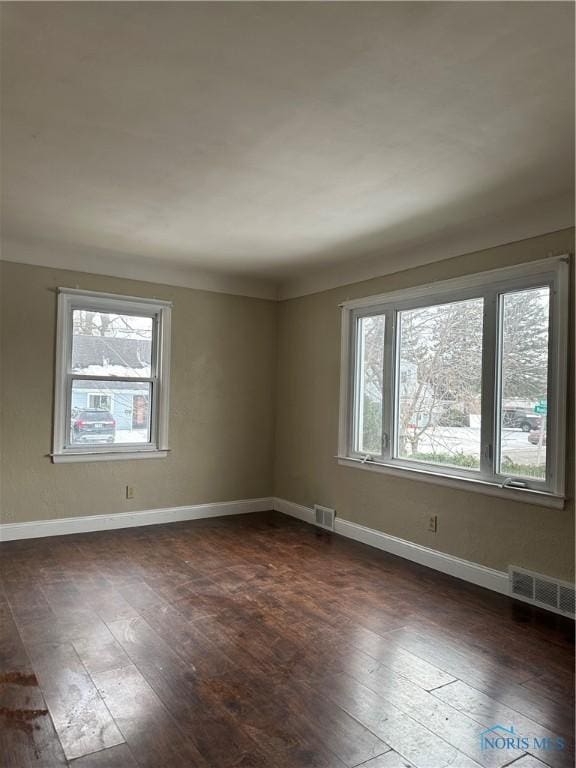 spare room featuring visible vents, dark wood finished floors, and baseboards