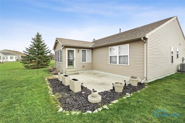 rear view of house featuring entry steps, a patio, a lawn, and cooling unit