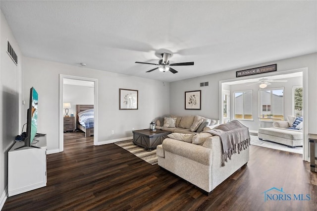 living area with dark wood-style floors, baseboards, visible vents, and ceiling fan