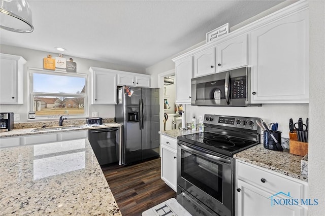 kitchen featuring appliances with stainless steel finishes, white cabinetry, a sink, and dark wood-type flooring