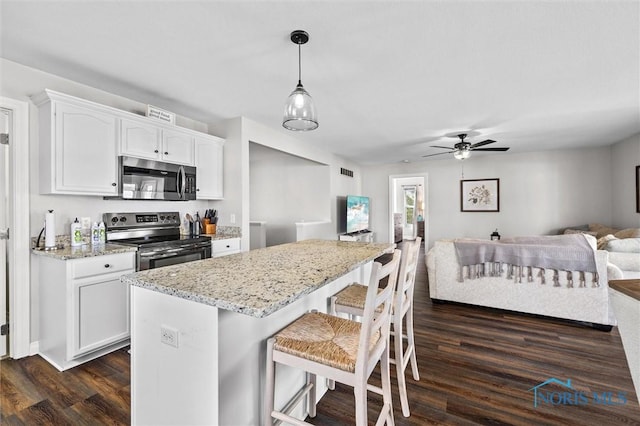 kitchen featuring appliances with stainless steel finishes, open floor plan, white cabinets, and dark wood-type flooring