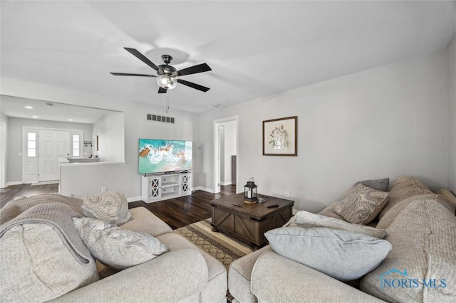 living room featuring ceiling fan, dark wood-style flooring, visible vents, and baseboards