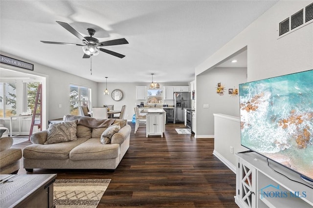 living area featuring baseboards, ceiling fan, visible vents, and dark wood-type flooring