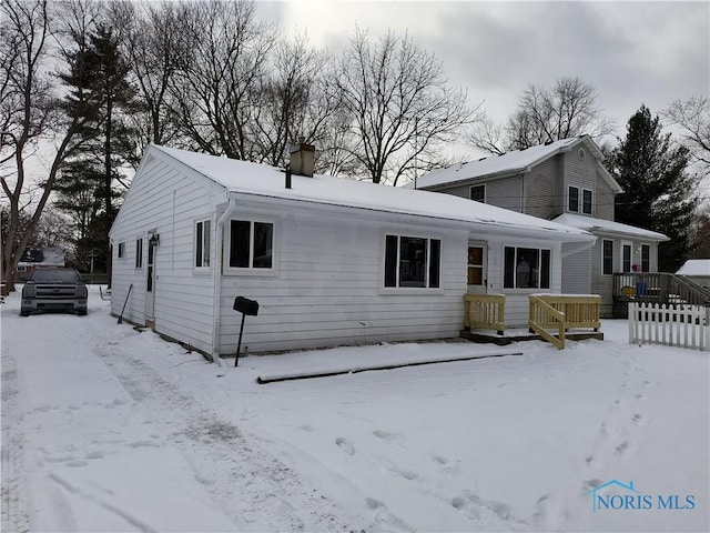 snow covered property featuring a garage and a chimney