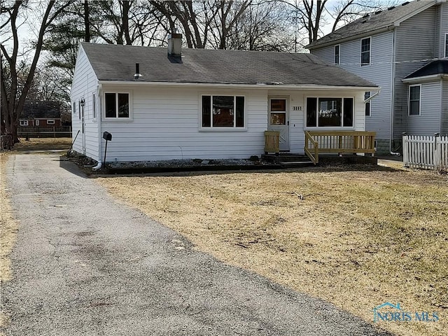 view of front of home featuring aphalt driveway, fence, and a chimney