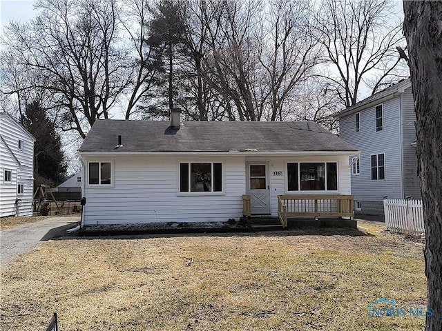 rear view of property with a lawn, a chimney, and fence