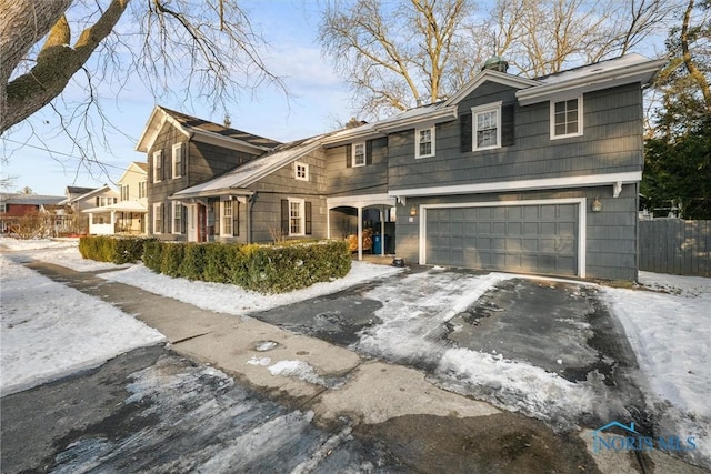 view of front facade with a garage, driveway, and fence