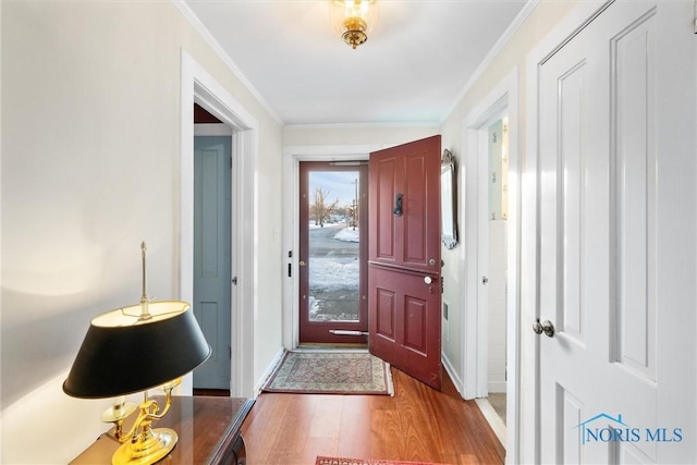 doorway to outside with crown molding, baseboards, and wood finished floors