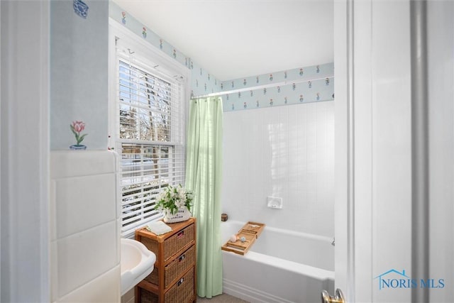 bathroom featuring a sink, shower / bath combination with curtain, and wallpapered walls