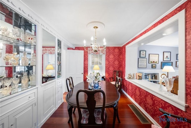 dining area featuring wallpapered walls, baseboards, visible vents, dark wood-style flooring, and a chandelier