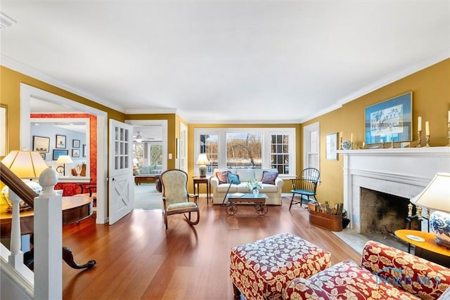 living room with a fireplace with flush hearth, crown molding, and wood finished floors