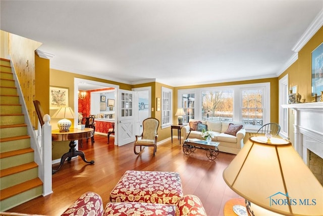 living area with wood finished floors, crown molding, baseboards, and stairs