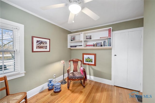 sitting room featuring a ceiling fan, baseboards, ornamental molding, and wood finished floors