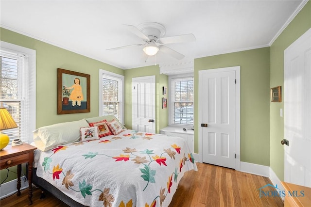 bedroom with ceiling fan, crown molding, baseboards, and wood finished floors