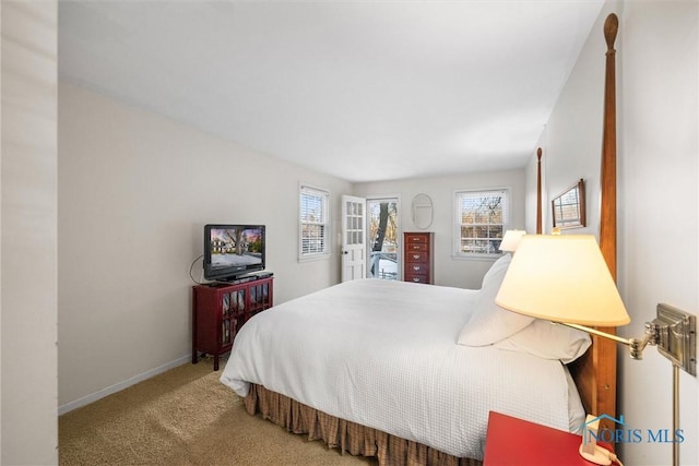 carpeted bedroom featuring multiple windows and baseboards