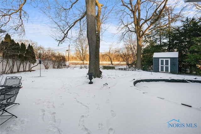 yard layered in snow featuring a storage unit and an outdoor structure