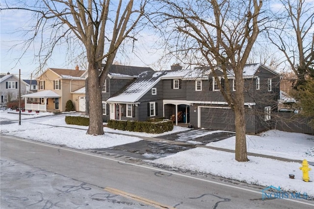 view of front facade featuring a garage, a residential view, and a chimney