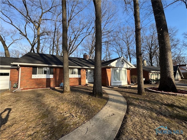 single story home with brick siding, an attached garage, and a chimney