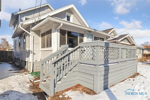 view of front of house featuring a wooden deck, stairway, fence, and a sunroom