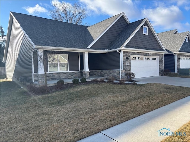 craftsman-style house featuring driveway, a shingled roof, stone siding, an attached garage, and a front lawn