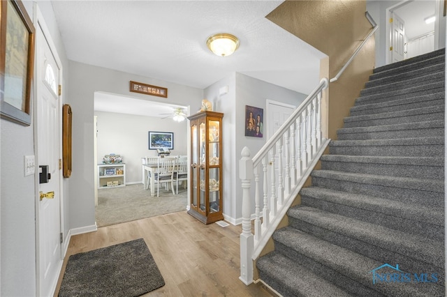 foyer entrance featuring stairway, wood finished floors, and baseboards