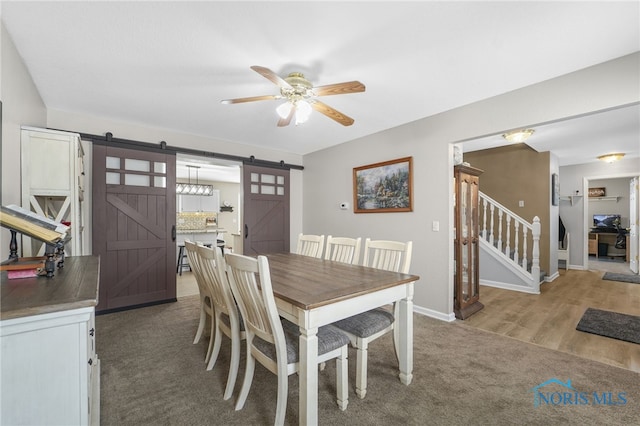 dining room featuring a barn door, baseboards, ceiling fan, stairs, and carpet floors