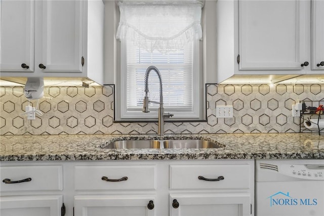 kitchen featuring white dishwasher, a sink, and white cabinets