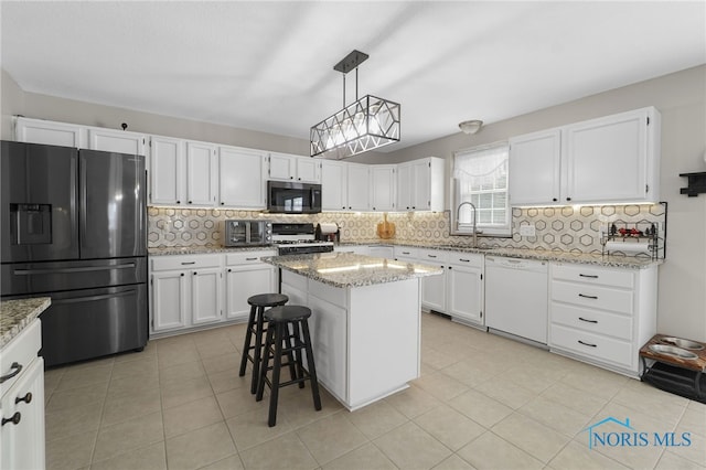 kitchen featuring stainless steel microwave, stove, white cabinetry, white dishwasher, and black fridge