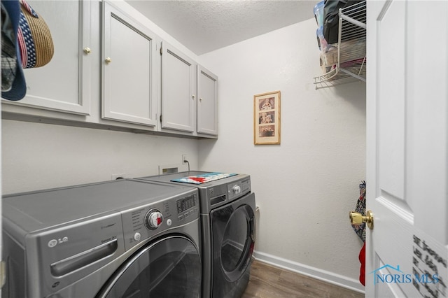 clothes washing area with cabinet space, baseboards, washer and clothes dryer, dark wood-style flooring, and a textured ceiling