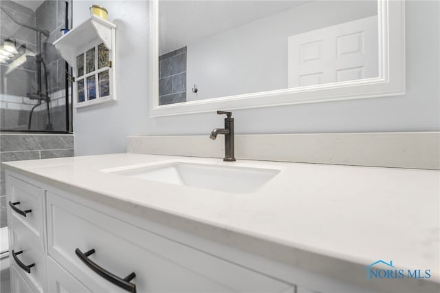 full bath with a tile shower and vanity