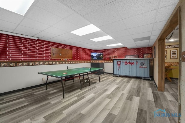 game room with a drop ceiling, wood finished floors, and baseboards