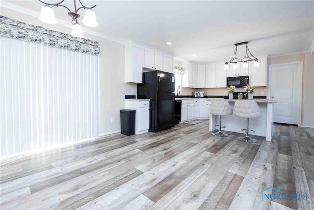 20391 Brown Ln, Weston, OH 43569 - kitchen featuring a kitchen island, white cabinetry, light wood-style floors, black appliances, and decorative light fixtures