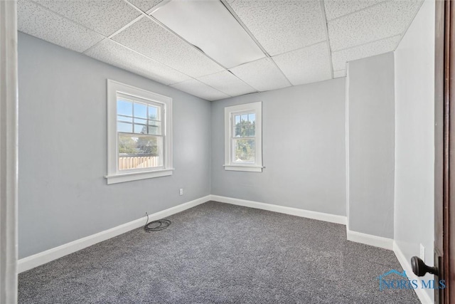 carpeted empty room with a paneled ceiling and baseboards