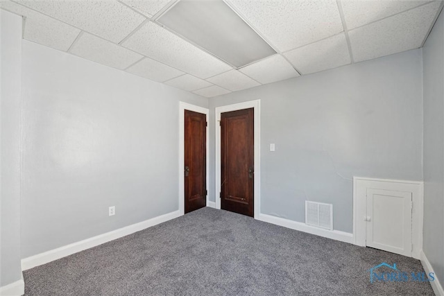 carpeted empty room with a paneled ceiling, baseboards, and visible vents