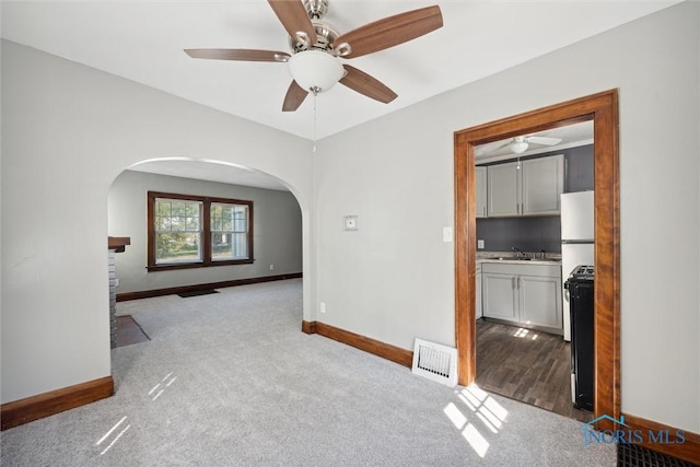 spare room featuring light carpet, a sink, visible vents, and baseboards