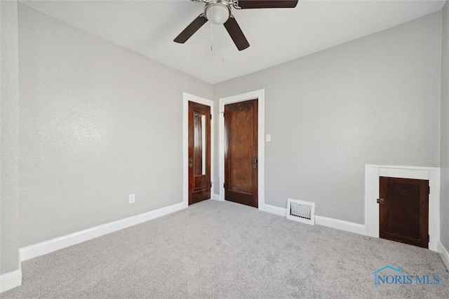 spare room with a ceiling fan, carpet flooring, visible vents, and baseboards