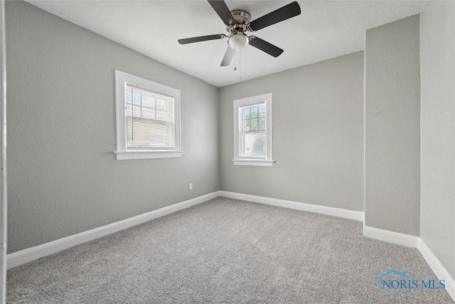 carpeted empty room with a textured wall, a ceiling fan, and baseboards