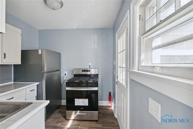 kitchen featuring baseboards, white cabinets, light countertops, appliances with stainless steel finishes, and dark wood finished floors