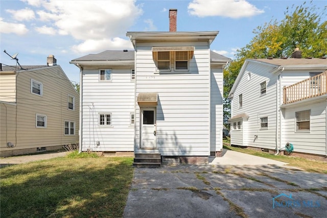 back of house with a patio area, a lawn, and a chimney