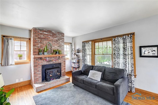 living area featuring wood finished floors, a wood stove, and baseboards