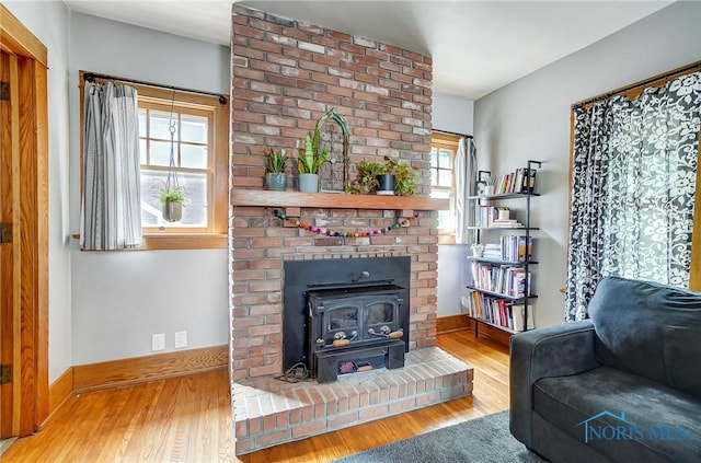 living area with wood finished floors, a wood stove, and baseboards